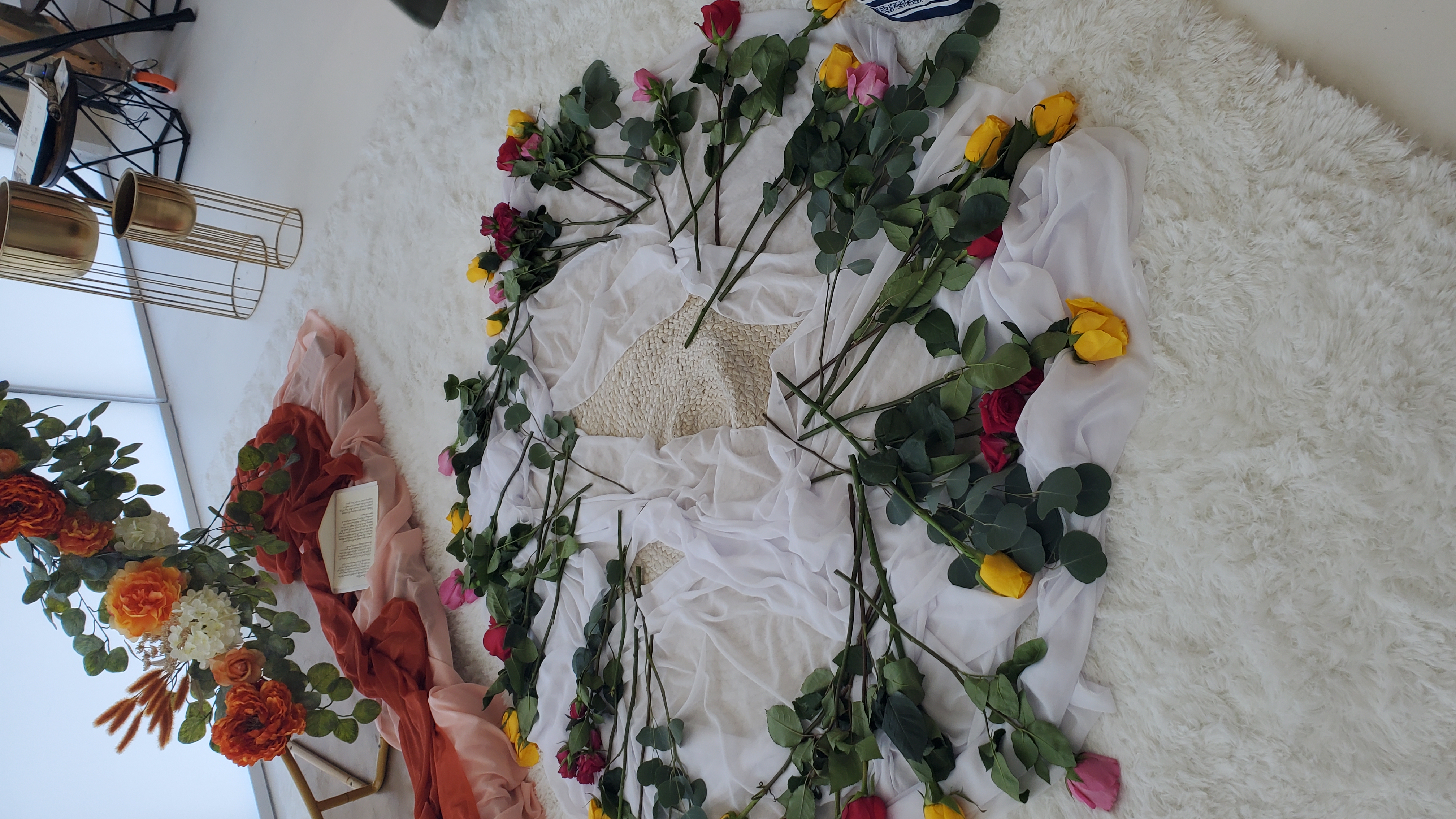 Montaje floral para ceremonia con pétalos y follaje alrededor de una mesa ceremonial