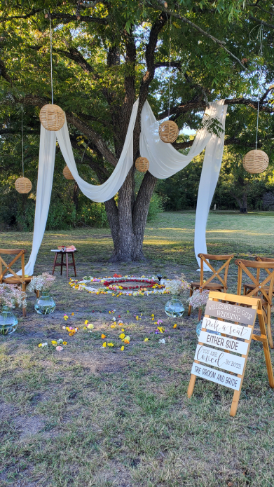 Outdoor Mayan wedding ceremony setup under large tree with white draping and hanging lanterns