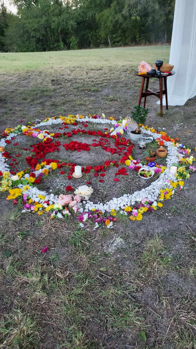 Close-up of heart-shaped Mayan ceremony space with flowers, candles, and ritual items