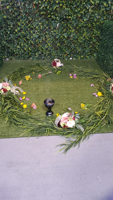 Indoor Mayan ceremony circle with greenery wall backdrop and floral arrangements