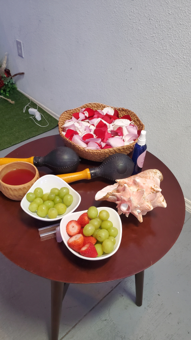 Table with fruit, maracas, rose petals, and items used in Mayan wedding ritual