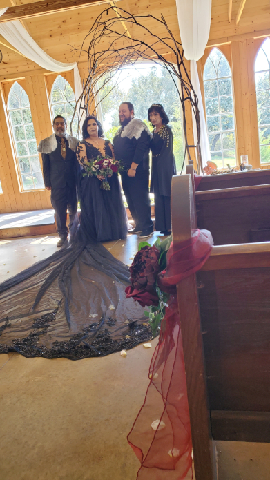 Foto grupal de boda vikinga con pareja y familiares bajo arco rústico de madera