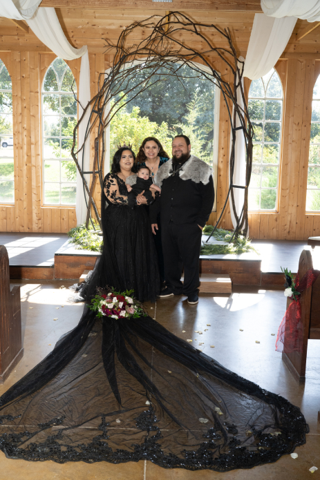 Pareja de boda vikinga con oficiante bajo arco ceremonial de madera con decoración floral
